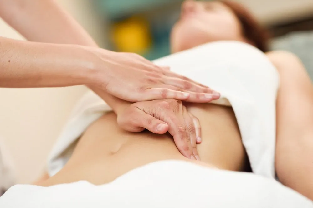 manos de fisiotyerapeuta en vientre de mujer