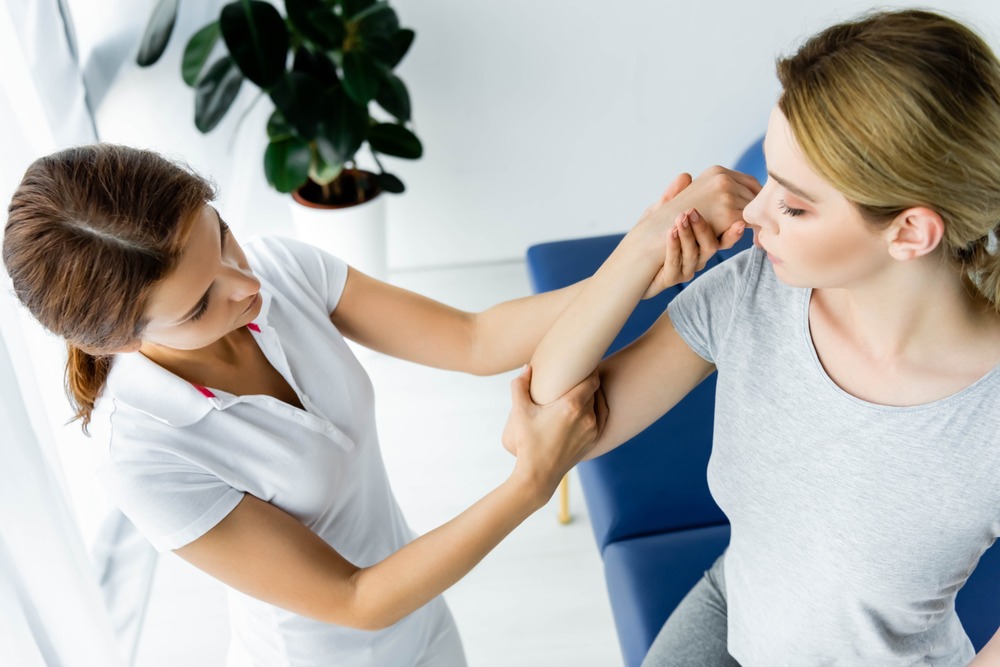 fisioterapeuta agarra brazo de paciente